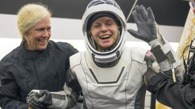 NASA astronaut Zena Cardman being helped out of the SpaceX Dragon Endeavour spacecraft . She is smiling at the camera