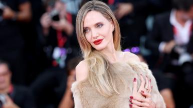 Angelina Jolie in a faux fur dress against a backdrop of photographers