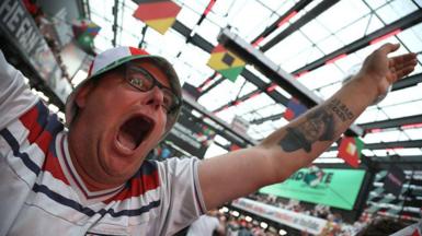 A football fan celebrates while watching the World Cup in a bar