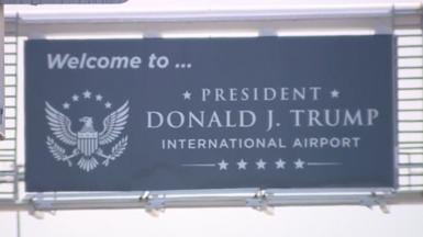 Image shows a sign saying "Welcome to President Donald J Trump International Airport"