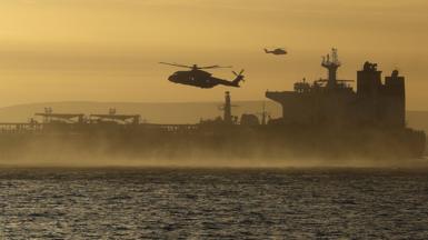 A helicopter in the sky above a seized tanker in the English Channel