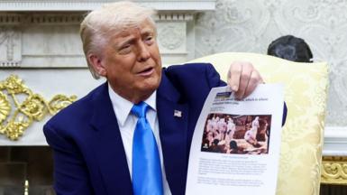 Donald Trump shows a copy of an article that he said was about white South Africans who had been killed, in the Oval Office of the White House in Washington