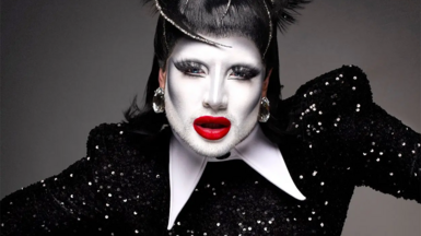 Danny Beard pictured with white make-up, red lipstick, and a sparkly black outfit