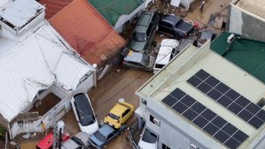 Cars are lumped together in two piles in a flooded street in the Philippines.