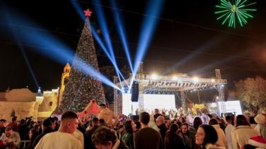 Palestinians light up a Christmas tree in Manger Square outside the Church of the Nativity, in Bethlehem