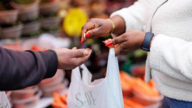 A customer pays for their shopping with coins at Ridley Road Market in Dalston, east London.
