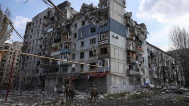 Members of the White Angel unit of Ukrainian police officers stand in front of a destroyed building in Pokrovsk