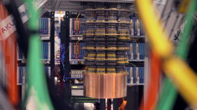 Google's Willow quantum computer is an oil barrel-sized series of round discs connected by hundreds of black control wires descending into a bronze drum suspended a metre from the ground in a lab.