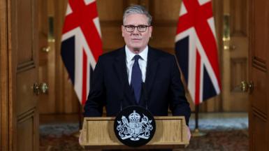 Sir Keir Starmer stands at a lectern in Downing Street flanked by two Union Jacks.