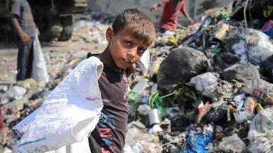 A Palestinian boy is searching for recyclables at a garbage dump in Deir el-Balah, 13 June 2024