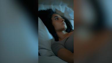 A woman with dark hair lies in bed