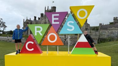 Deio a Brynmor wrth yr arwydd croeso