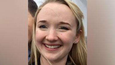 A close-up photo of Jessica Brady who is smiling broadly and looking directly at the camera, with long blonde hair, brown eyes and an earring visible in her left ear