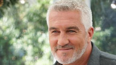 A man with silver hair and stubble smiles