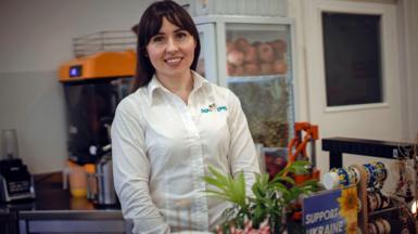 Maryna with brown hair and wearing a white shirt smiles at the camera