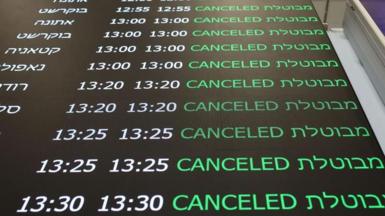 A flight status display shows cancelled flights in the departure terminal at Ben Gurion Airport near Tel Aviv