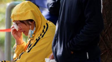 A woman reacts outside the Kwong Fuk Community Hall where relatives identify family members from photos