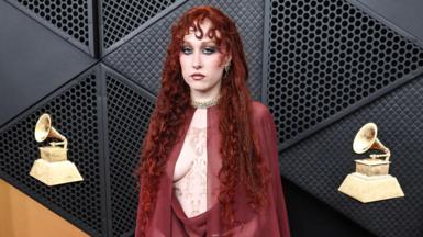 Chappell Roan in chiffon blood red Mugler dress and cape on the Grammys red carpet