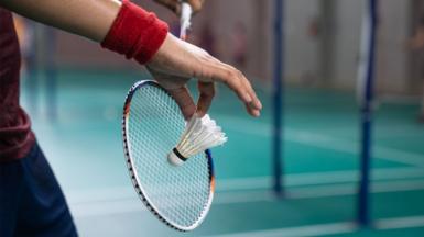 A person holds a badminton racket and shuttlecock