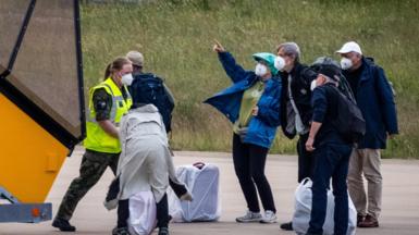 People wearing protective clothing disembark a plane in the Netherlands