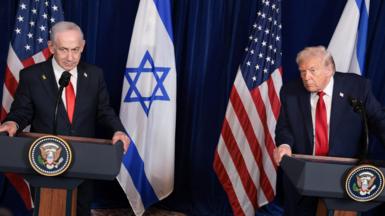 Trump and Netanyahu speaking at a conference, while both wearing suits with red ties with Israeli and US flags in background