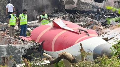 Photo from Air India plane crash site, taken on June 13, 2025 in Ahmedabad. The tail of the plane is visible with men inspecting it. 