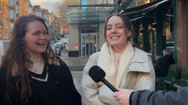 Two young women are looking and smiling at the camera in Glasgow's west end