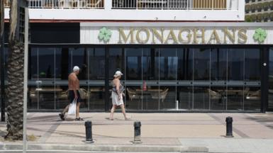 A man and woman walk past Monaghans bar in Costa del Sol