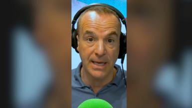 A man, Martin Lewis, wearing headphones, looking at the camera, with a green mic in front.
