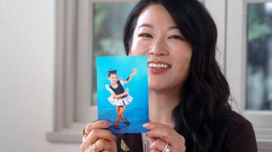 Headshot of Arden Cho smiling holding a  childhood photo
