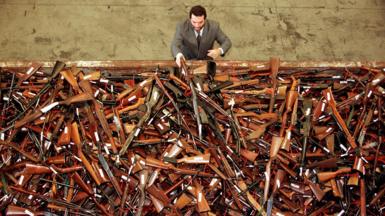 Mick Roelandts, firearms reform project manager for the New South Wales Police, looks at a pile of about 4,500 prohibited firearms in Sydney that have been handed in over the past month under the Australian government's buy-back scheme, July 28 1997.