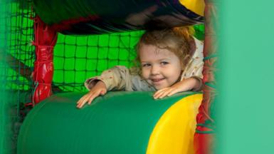 A girl in a green softplay area