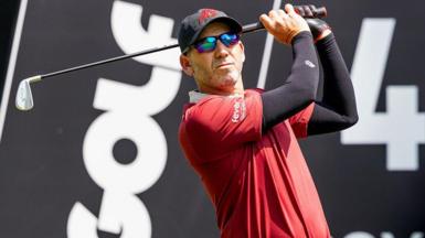 Sergio Garica tees off during a LIV Golf tournament with the branding in the background
