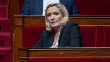 Marine Le Pen sits in the French National Assembly. She has short blonde hair and is wearing a dark blazer