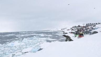 A view of the old city of Nuuk, Greenland, with coloured wooden houses surrounded by snow and ice