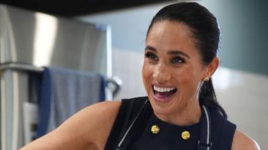 Meghan Markle wearing a sleeveless black dress and apron