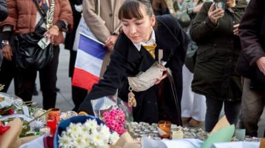 A woman lays flowers at a temporary memorial to the victims of the 13th November 2015 Paris terrorist attacks at Place de la Republique, on the tenth anniversary of the attacks, on November 13, 2025 in Paris, France.