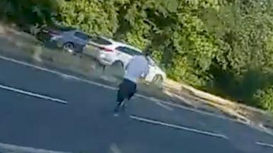 A man is running across a road away from police