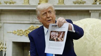 U.S. President Donald Trump holds up a printed article from "American Thinker" while accusing South Africa President Cyril Ramaphosa of state-sanctioned violence against white farmers in South Africa 