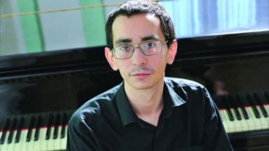 Pavel Kushnir sitting in front of a piano