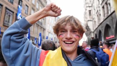 A young man wearing a German flag and with the German flag on his cheeks looks happy in Munich, 13 June 2024