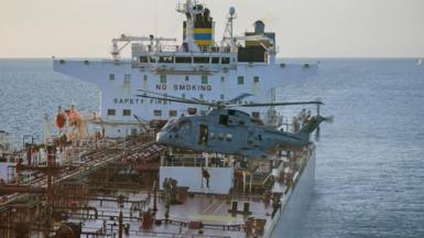 A helicopter hovers over the deck of an oil tanker  