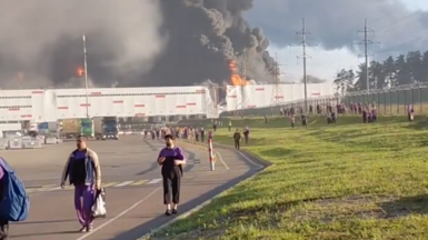 people walk away from a burning warehouse