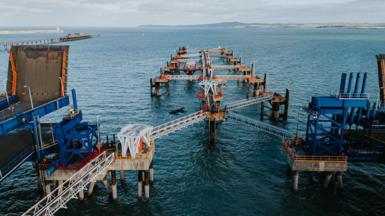 Holyhead port walkways jutting out of the sea. There is an object jutting out of the sea which seems to have broken off of the port.