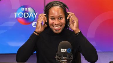 Holding headphones on his head, BBC Radio 4 Today Christmas guest editor Prof Jason Arday smiles at the camera in the studio. 