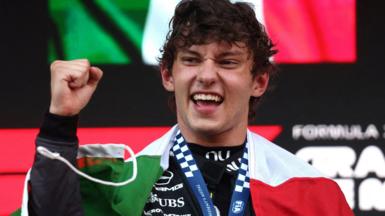 Kimi Antonelli clenches his fist with the Italian flag draped around his shoulders after winning the Monaco Grand Prix