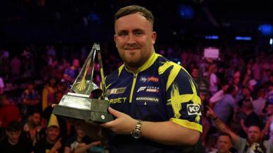 Luke Littler holding the Premier League trophy