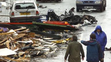 Security experts examine the charred remains of the vehicle thought to have contained the bomb which exploded in Omagh's shopping area in Northern Ireland, August 16, 1998.
