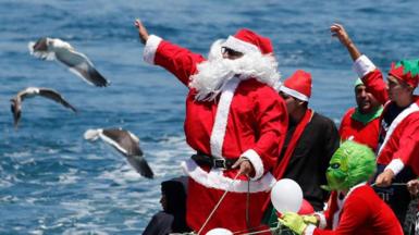 Fishermen dressed as Santa and the Grinch on a boat in Valparaiso Bay, Chile