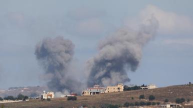 Plumes of smoke are seen above a house